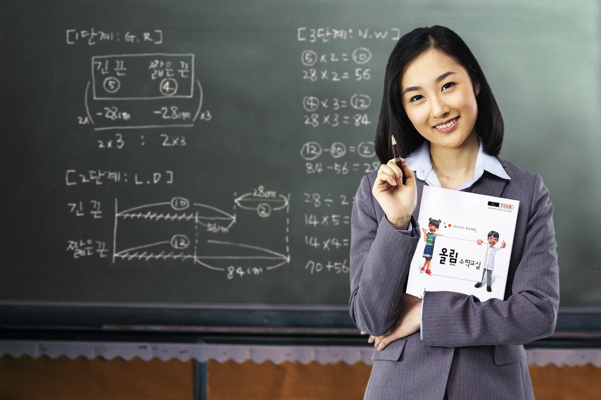 칠판 앞에서 올림수학 교재를 든 선생님